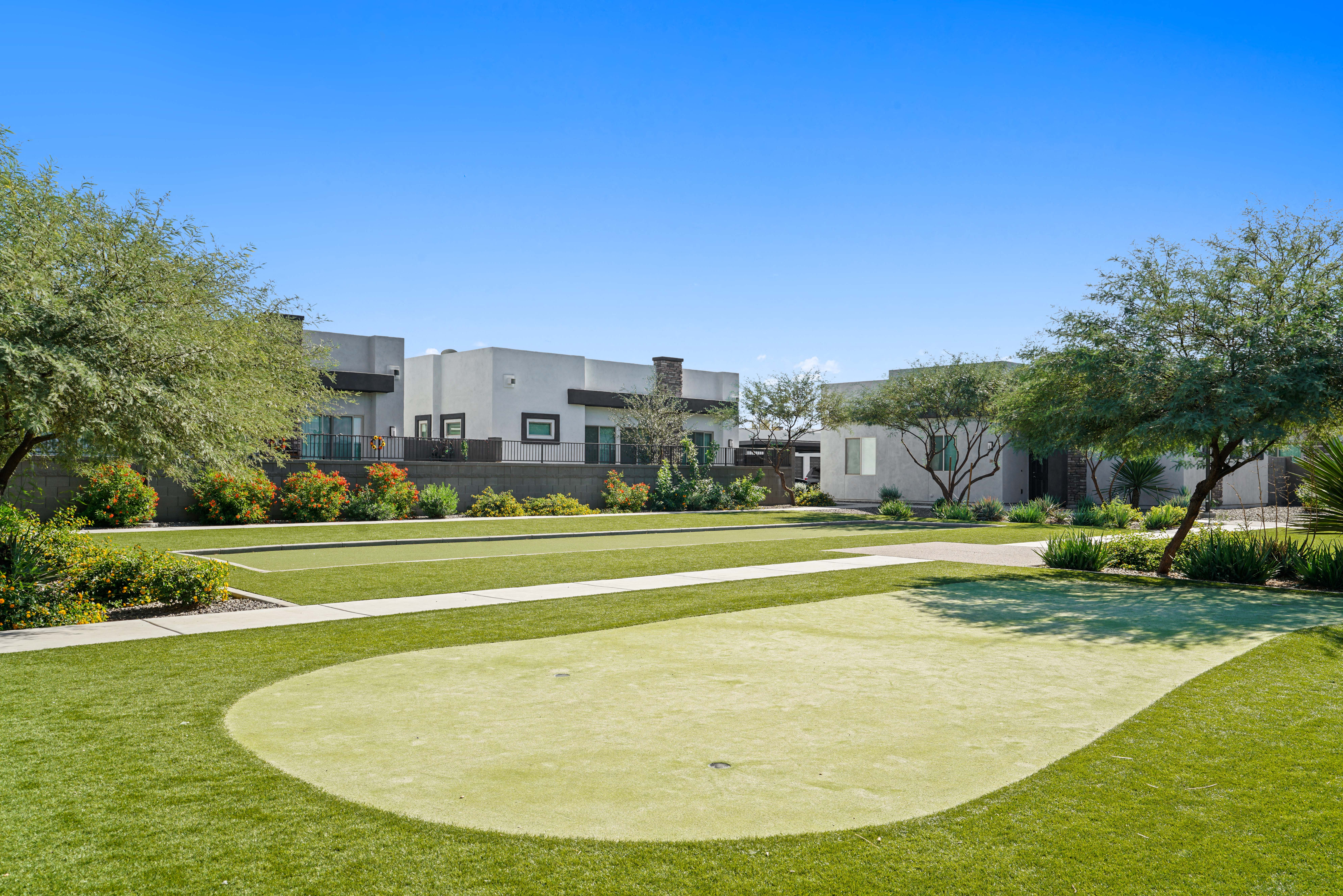 a yard with grass and trees and buildings in the background at Olive Queen Creek Apartments, Queen Creek, AZ, 85142